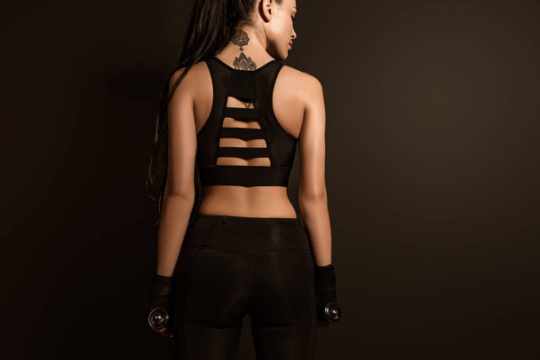 Visszapillantás sportos nő súlyzókkal elszigetelt fekete - Fotó, kép