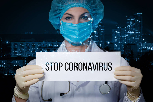ストップコロナウイルスの概念。医者は市内を背景にコロナウイルスを止めるというサインを持っています. - 写真・画像