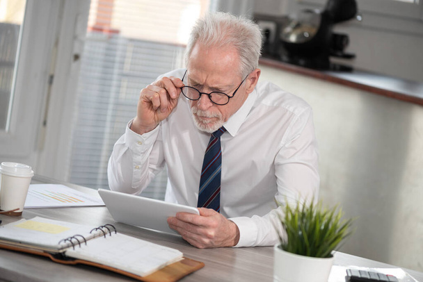 Senior businessman using digital tablet at workplace - Photo, Image