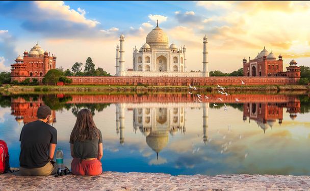 タージ・マハル(Taj Mahal)美しい空と水の反射が楽しめる日没時の歴史的な白い大理石の霊廟アグラ・インディア(Agra India)のヤムナ川のそばのメータブ・バグ(Mahtab Bagh)に座って - 写真・画像