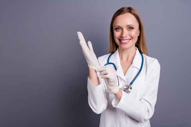 Close-up portrait of nice attractive blonde girl experienced doc specialist surgeon putting rubber gloves on preparing surgery isolated over grey violet pastel color background - Foto, imagen