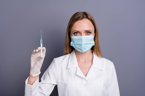 Close-up portrait of nice attractive blonde girl qualified experienced doc specialist expert holding in hands syringe safety assistance isolated over grey violet pastel color background - Foto, immagini
