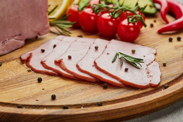Sliced ham with spices, lettuce, avocado and tomatoes on wooden cutting board. old meat plate  Fresh prosciutto - Photo, Image