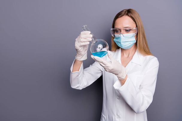 Portrait of nice attractive blonde girl skilled qualified experienced doc biologist holding in hands test tube analyzing influenza isolated over grey violet pastel color background - Fotó, kép