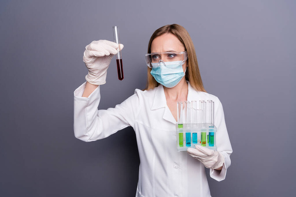 Portrait of nice attractive focused blonde girl smart clever doc biologist holding in hands test tubes experiment analysis analyzing biology isolated over grey violet pastel color background - Photo, Image