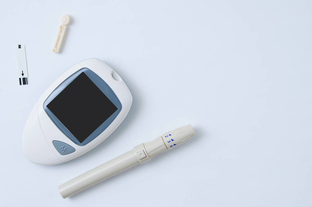 Electronic blood glucose meter, lancet and test strip to determine blood sugar. White background. - Foto, afbeelding