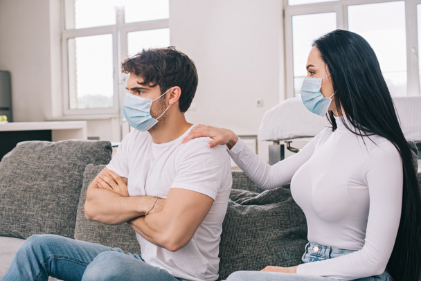 ofendido hombre y mujer en máscaras médicas en casa durante el aislamiento personal
 - Foto, imagen
