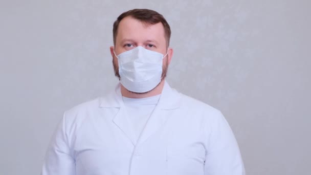 Male in a protective mask and a white shirt looks at the camera, close-up. Hygiene concept. prevent the spread of germs and bacteria and avoid infection with the crown virus. copy space - Video
