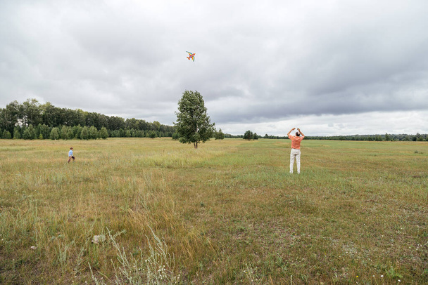 Grandfather and grandson fly a kite on the field. Rural area, Russia. - Fotografie, Obrázek