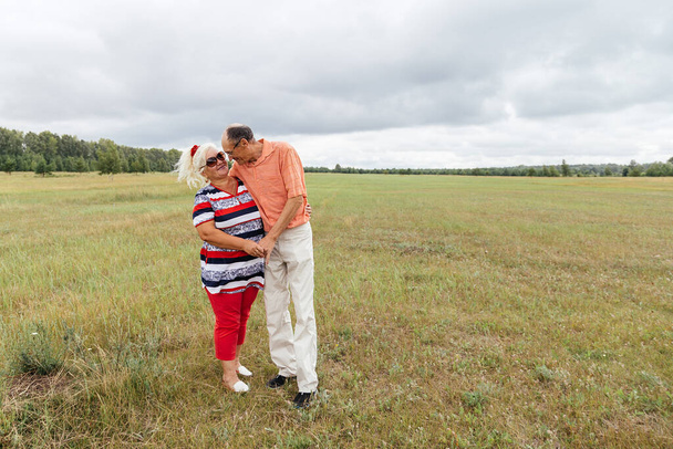 An elderly couple enjoy a walk in a field. Rural area, Russia. - 写真・画像