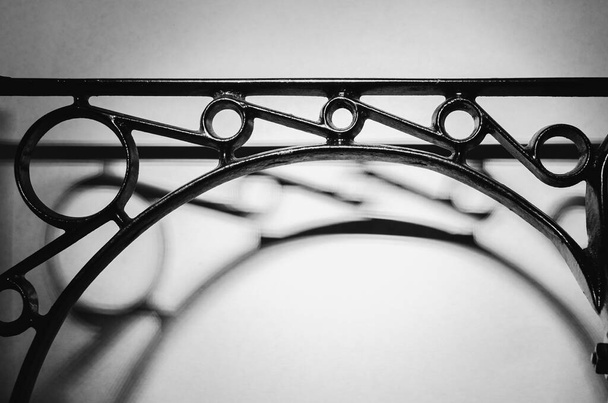 Estructura simétrica de hierro fundido negro con sombras oscuras sobre fondo blanco
 - Foto, imagen