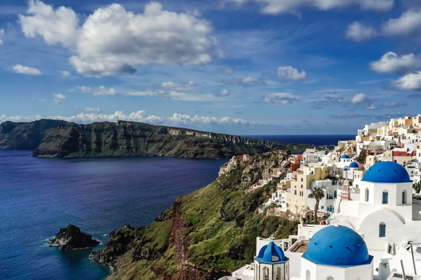 iglesias de cúpula azul cerca de casas blancas y el mar tranquilo en santorini
  - Foto, imagen