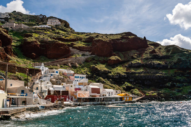 SANTORINI, GREECE - APRIL 10, 2020: white houses on hill near aegean sea against sky with clouds  - Foto, imagen