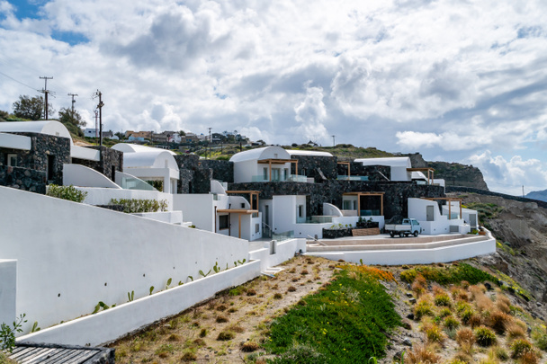  Weiße Häuser in der Nähe grüner Pflanzen gegen wolkenverhangenen Himmel  - Foto, Bild