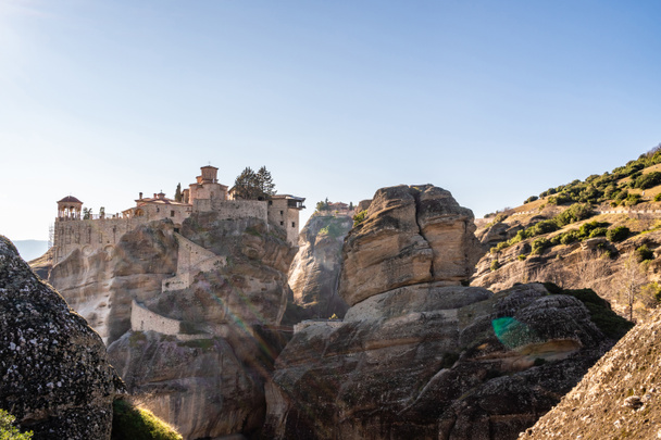 sunlight on orthodox monastery on rock formations against blue sky in meteora  - Photo, Image