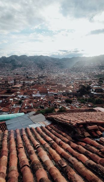CUSCO, PERU - CIRCA NOVEMBER 2019: aerial view of ancient town of Cusco with old houses with orange tile rooftops surrounded by mountains. - Foto, afbeelding