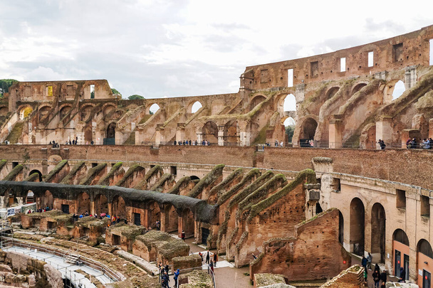 ROME, ITALY - APRIL 10, 2020: people near ruins of historical colosseum against cloudy sky  - Foto, Imagen