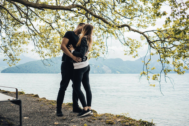 Całująca się para pod drzewem na plaży nad jeziorem Lucerna, Szwajcaria - Zdjęcie, obraz