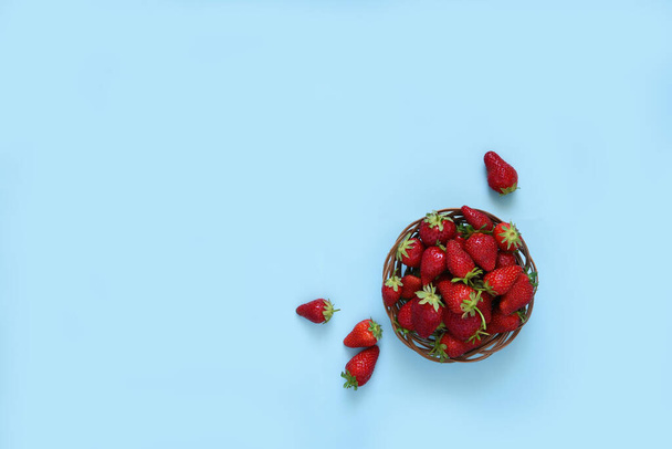 Fresh strawberries in a goat on a blue background. Top view with copy space. - Fotografie, Obrázek