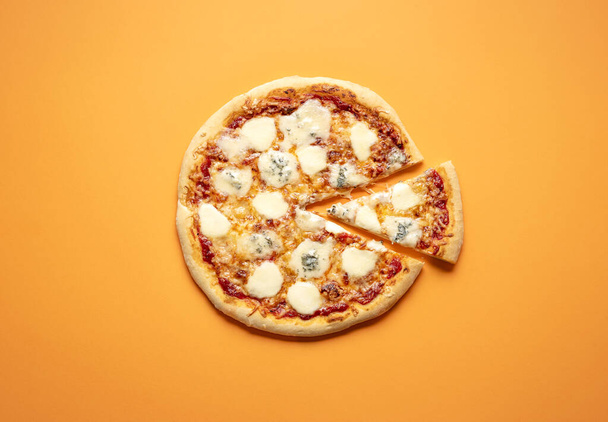 Pizza Quattro Formaggi maison après une recette italienne. Classic vue de dessus de pizza simple sur un fond de couleur orange. Pizza avec beaucoup de mozzarellas, parmesan et gorgonzola
. - Photo, image