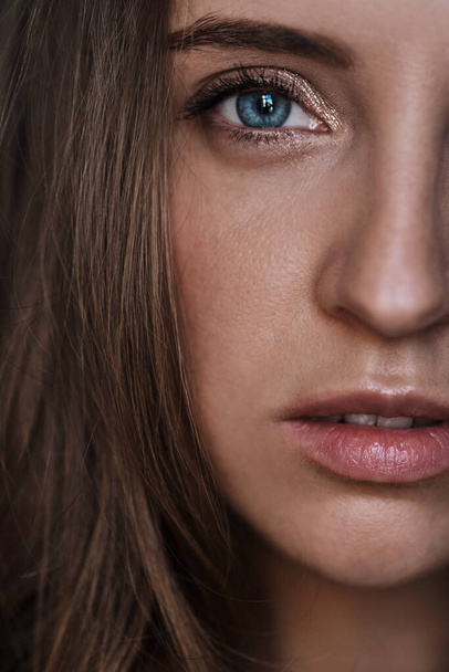 Close-up portrait of young beautiful stylish woman with long brown wavy with blue eyes, half face. Pretty calm girl - Photo, Image