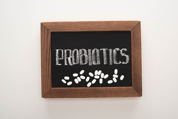 vista dall'alto della lavagna con probiotici lettering con pillole su sfondo bianco
 - Foto, immagini