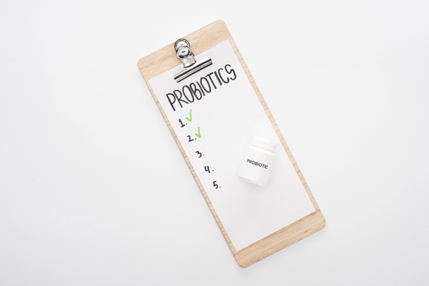 vista superior del portapapeles con probióticos lista vacía y pastillas sobre fondo blanco
 - Foto, Imagen