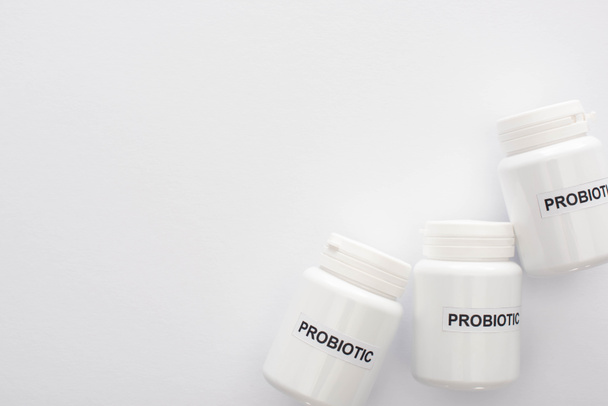 bovenaanzicht van containers met probiotische belettering op witte achtergrond - Foto, afbeelding