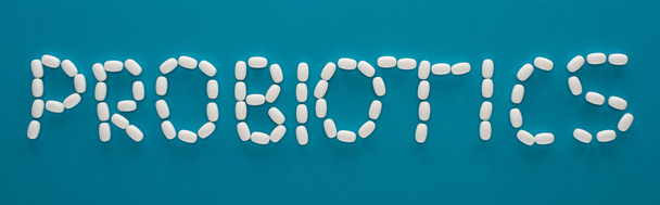 vista superior de letras de probióticos hechas de píldoras sobre fondo azul, orientación panorámica
 - Foto, Imagen