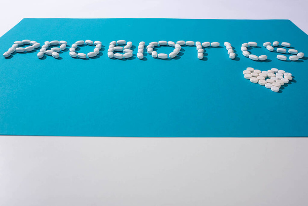 probiotics lettering and heart made of pills on blue and white background - Fotografie, Obrázek