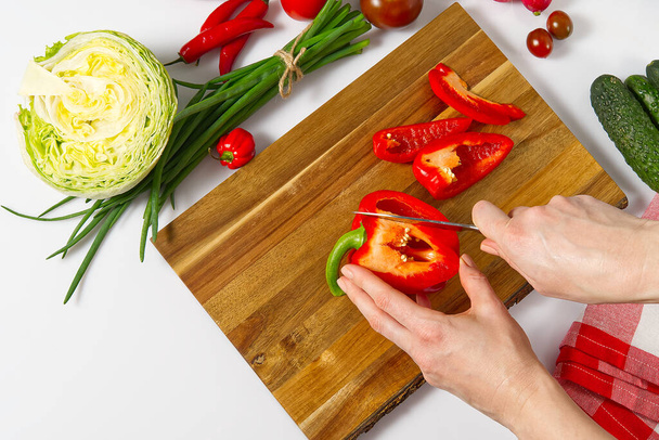 Salat aus frischem Gemüse in einem Teller auf einem Tisch. Salatschüssel mit Gemüse und Gemüse auf weißem Tisch. Frauen bereiten Gemüsesalat zu - Nahaufnahme. Heimische Küche. Vegetarisches Essen. - Foto, Bild
