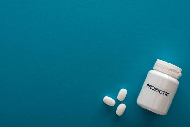 vue du dessus du récipient probiotique blanc avec des pilules sur fond bleu
 - Photo, image