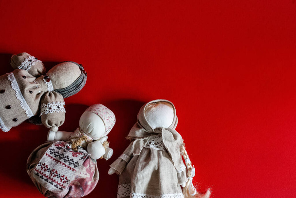 Ručně vyráběné textilní panenky na červeném pozadí. Bohaté panenkyv kapesnících v etnickém stylu ukrajinských a ruských tradic, slovanský suvenýr. Místo pro text. Pozadí. - Fotografie, Obrázek
