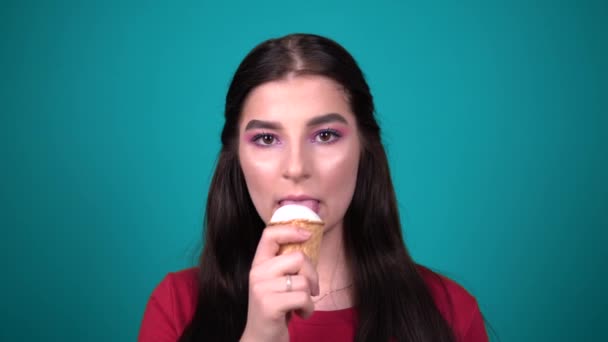 jonge vrouw eten wit ijs genieten snoep geïsoleerd op blauwe achtergrond - Video