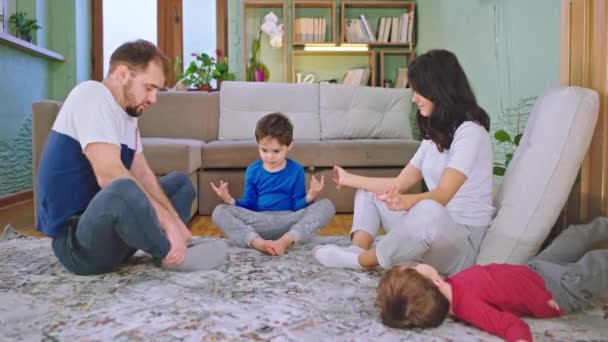 Em casa passar o tempo juntos família carismática com dois filhos praticando poses de ioga na sala de estar eles têm um tempo perfeito juntos
 - Filmagem, Vídeo