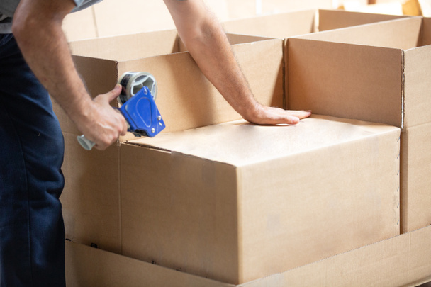Man packing with adhesive tape in warehouse, CARGO SHIPPING - Photo, Image