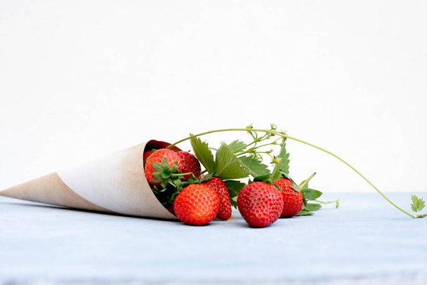 Papierkegel mit roten Erdbeeren, Blättern - Foto, Bild