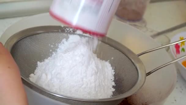 El cocinero tamizar el azúcar en polvo a través de un tamiz de metal en un tazón. Cocinar en casa
 - Metraje, vídeo