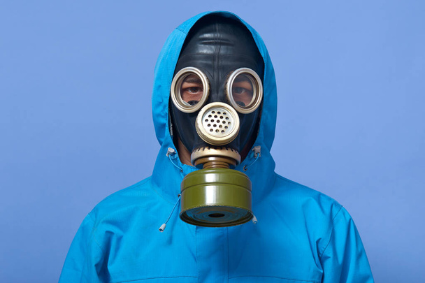 Image of ecologist wearing gas mask frights with pouring dangerous chemicals to ground, world industry pollutes atmosphere with tons of dust and other harmful things. Ecological problems concept. - Фото, зображення