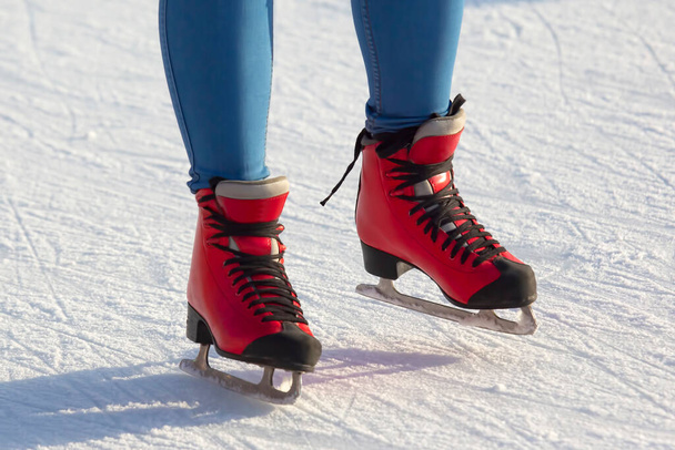 Buz pistinde kırmızı paten giyen ayaklar. Hobiler ve boş vakitler. kış sporları - Fotoğraf, Görsel