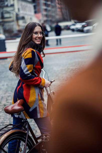 Positive woman with a bike in the street smiling stock photo - Foto, afbeelding