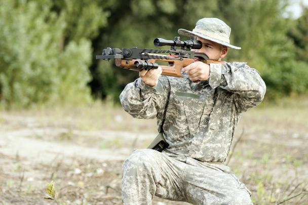 Sotilaspukuinen metsästäjä tai sotilas tähtää ja ampuu jousipyssyllä.
. - Valokuva, kuva