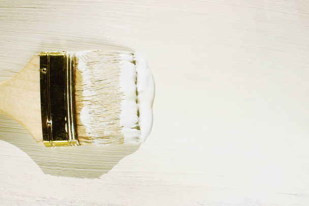 Brush with white paint on wooden background. Objects, backgrounds, repairs, art concept. - Photo, Image