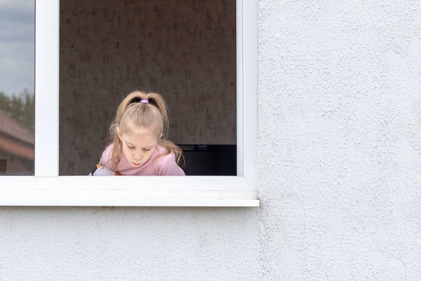 Dítě sedí za odlivu v okně v jeho rukou hračka. Podívej se na nás. Nebezpečná situace - Fotografie, Obrázek
