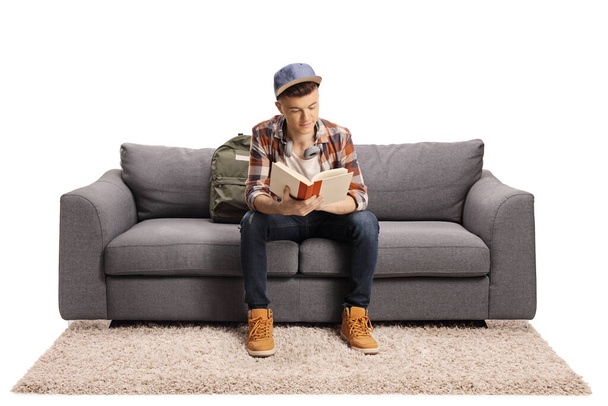 Male student sitting on a sofa and studying isolated on white background - Foto, afbeelding