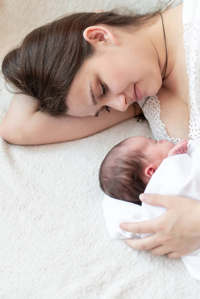 motherhood, infancy, childhood, family, care, medicine, sleep, health, maternity concept - portrait of mom with newborn baby wrapped in diaper on white background, place for text, close-up, soft focus - Foto, Imagen