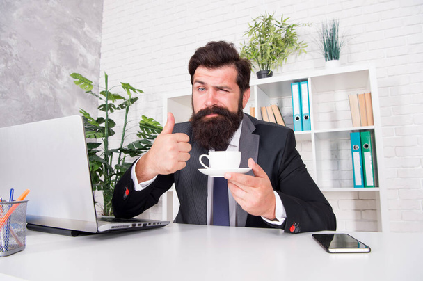 Best way to enjoy coffee. Bearded man show thumbs up to coffee cup. Businessman drink coffee in office. Coffee break. Hot drink. Breakfast tea. Morning beverage. Simple pleasures - 写真・画像