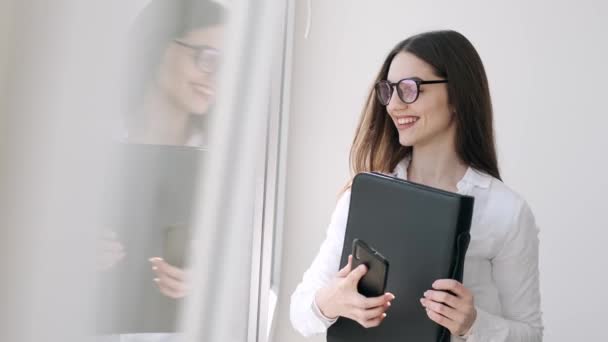 Beautiful woman in glasses is near the window smiling - Felvétel, videó