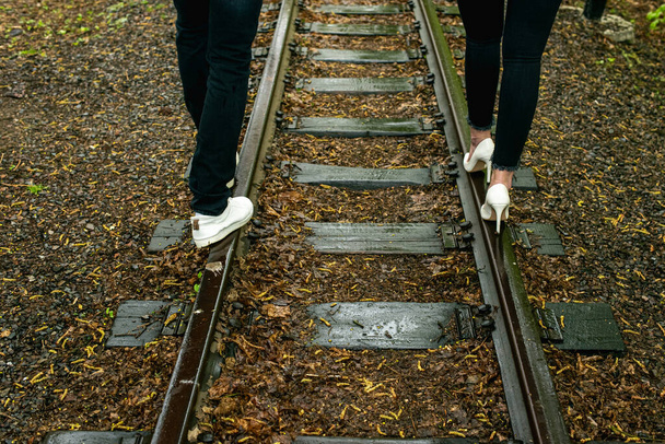 Mann und Mädchen laufen im Regen auf einem Bahngleis - Foto, Bild