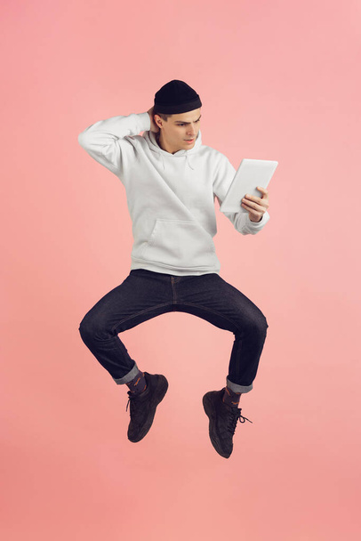 Caucasian young mans modern portrait on pink studio background in high jump - Foto, afbeelding